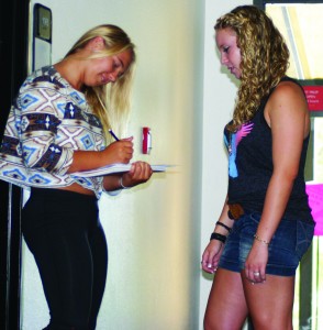 Time for signatures: Nicole Zorin (right) tries to get signatures from  as many students as possible. Here Sophomore KC Brendel (left) signs the petition. Photo by Charlotte Louisa - Staff Photographer