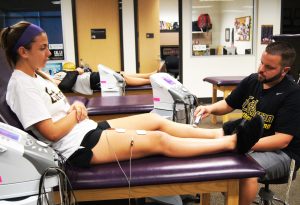 Keeping players on the field: Assistant Athletic Trainer Cody Owens works on freshman Kali Youngdahl of the Regals soccer team before their practice. Photos by Hailey Moore - Staff Photographer