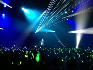 Miku Hatsune on stage with fans waving their glow sticks