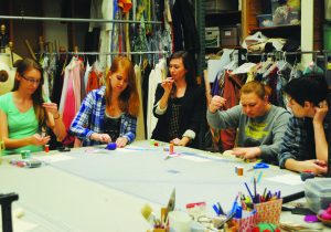 Costume design: Noelle Raffy (left) helping students Dani Kuss and Nikki Page learn how to properly thread a needle for the upcoming semester. 
