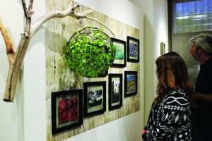 Two guests of the art show looking on at one of the pieces created by an artist. 