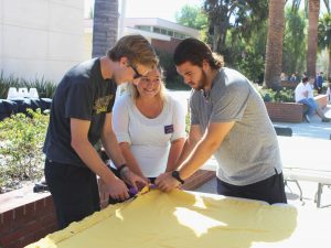 Jessamine Gilman-Vorm, Jeffrey Roberts and Eric Flores of the Cal Lutheran Community Service Center starts 6 Minutes of Service by tying the first knots on one of the many blankets created for Syrian refugees.  Photo by Andrew Turley - Staff Photographer