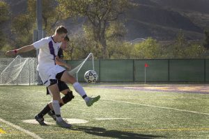 Sophomore forward Brandon Kearney fights off a Whittier defender Oct. 3. Kearney scored his conference-leading 10th goal in the double-overtime loss. Photo by Brady Mickelson - Staff Photographer