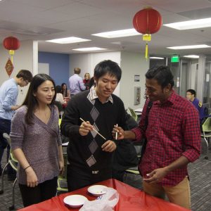 Toby Chan teaches Badarinath Peddireddy how to properly use chop sticks at the Chinese New Year event on Feb. 8. in the International Student Services Lounge.  Photo by Brady Mickelson - Multimedia Journalist