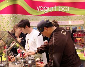 Junior Matthew Kubly placed toppings on his free Menchies frozen yogurt sponsored by ASCLUG programs board. Photo by Madi Schmader  Staff Photographer