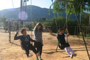 Cal Lutheran student Natalie Elliot (middle) helps a fellow Cal Lutheran student (left) get in sync on the swings with one of Rancho Sordo Mundo's hearing-impaired students during recreation time after breakfast on Monday.  Photo courtesy of Elizabeth Roemisch