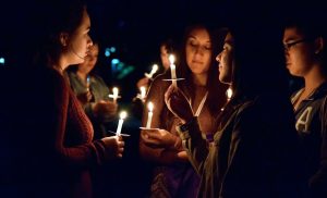 Candle light illuminates sophomore Mao Kohara’s smile as she stands among her friends during the Take Back The Night candle light vigil. “I felt like by all of us coming together and recognizing sexual violence and learning about it, we could minimize this problem,” Kohara said.  Photo by Roman Valenzuela - Staff Photographer