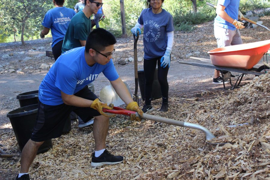 Jordon shovels mulch into the wheelbarrows that other students would distribute onto the trail