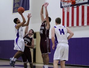 Junior guard #0 Kenneth Moffett goes up for a jump shot and senior center  #14 Jacob Dawe comes up to ensure the two points fall for the Kingsmen. Staff Photographer--Mary Crocker