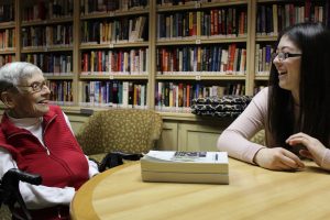 Catching-up: Ninety-two-year-old Sylvia Macks (L) listens to Cal Lutheran senior Gina Domergue (R) share memories from her travels abroad as they sit in the library of The Reserve retirement community. Photo by Amanda Souza- Staff Photographer
