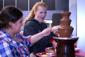 Taylor Trujillo and Brittany Devalk enjoy the chocolate fountain and other treats at the Valentine's Day Bash. Photo by Mary Crocker - Staff Photographer