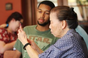 Volunteer Micah Franklin teaches Miho Vukmirovich how to use the panorama photo feature on her phone. Photo by Jacqueline Rodriguez - Photo Editor