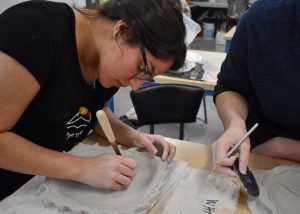 "It gives us a chance to do something we’ve never done before," said undergraduate student Nakiessa Abbassi about the workshop as she designs her white clay pottery plate. Photo by Aliyah Navarro- Photojournalist