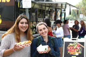 Seniors Natalie Mendez (left) and Lauren Curl (right)  stop by Picnic Day after class and enjoy the wide variety of food offered. Photo by Jovanni Garcia - Photojournalist
