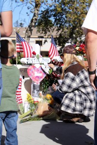 Borderline memorial: Laura Lynn Meek, mother of Cal Lutheran alumnus Justin Meek, places a rose on his cross at the memorial for the victims of the Borderline Bar & Grill mass shooting. The memorial was set up ouside of the Thousand Oaks venue for community members to pay tribute.  Photo by Arianna Macaluso-Photo Editor