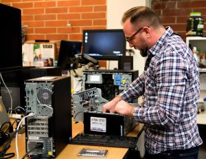 Chris Ion, a computer systems specialist, at work in the ITS department. One of his duties is ensuring everything is backed up, which makes it impossible to lose any information regarding the school. Photo by Katie May- photojournalist. 