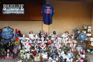 A more permanent home: Family pictures, hats, cards, love notes, flowers and candles lay at the feet of the 12 hand-crafted Borderline victim memorials just outside the bar. A more permanent memorial is in the works. Photo by Joc Smith - Photojournalist