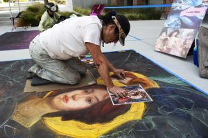 Chalk artist Lorelle Miller went against the theme of imagination and drew this picture by Edgar Maxence. She said she wanted something that showed healing for the Ventura community. Photo by Jessica Colby - Photojournalist