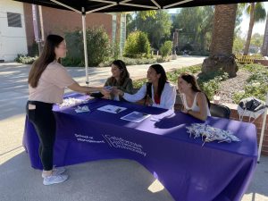 Andrea Villasenor hands a flier to a student at the Women in Business Club recruiting event at The Spine on Tuesday Nov. 30, 2021 from 11 a.m to 12:30 p.m.