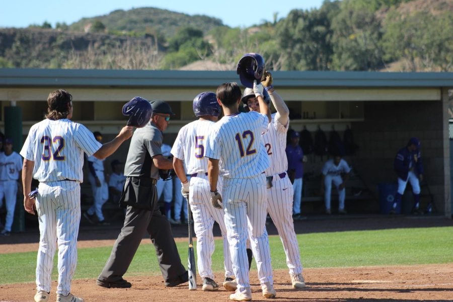 Kingsmen celebrate with one another at home after the team hits a grand slam