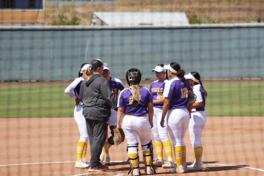The Regals softball team gathers at the mound to discuss plans for the at-bat.