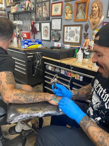 Tattoo Artist Brandon Hernandez tattooing a butterfly on someones hand.