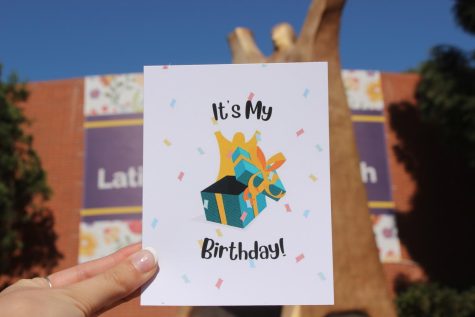 A sticker that says "It's my Birthday" with a picture of Gumby coming out of a present being held in front of the Enormous Luther statue.