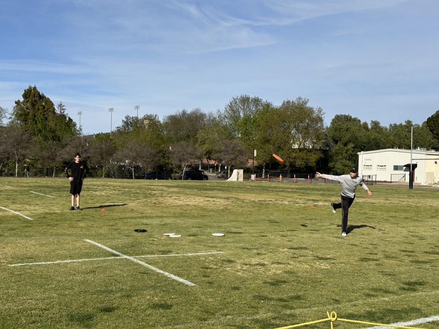 A member of the Cal Lutheran frisbee club throws the disc as another club member watches on.