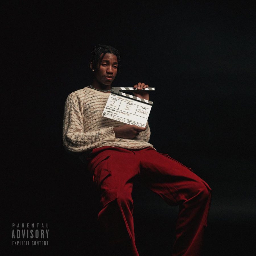 Senior Lothario Parris, dressed in white, tan sweater with red pants. He is sitting on something invisible to the viewers and is holding a clapperboard or movie slate that says the name of the album and its release date.