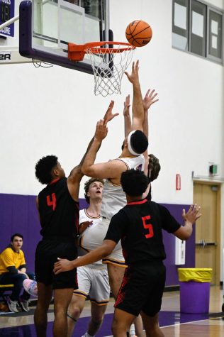 A member of the Kingsmen basketball team attempts to make a basket.