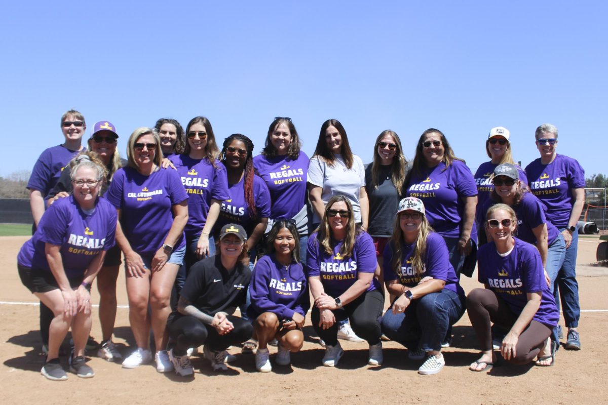 All 18 Regals Softball alumni in attendance pose for a picture with Head Coach Kecia Davis on the field after the Alumni Appreciation Day ceremony. 
