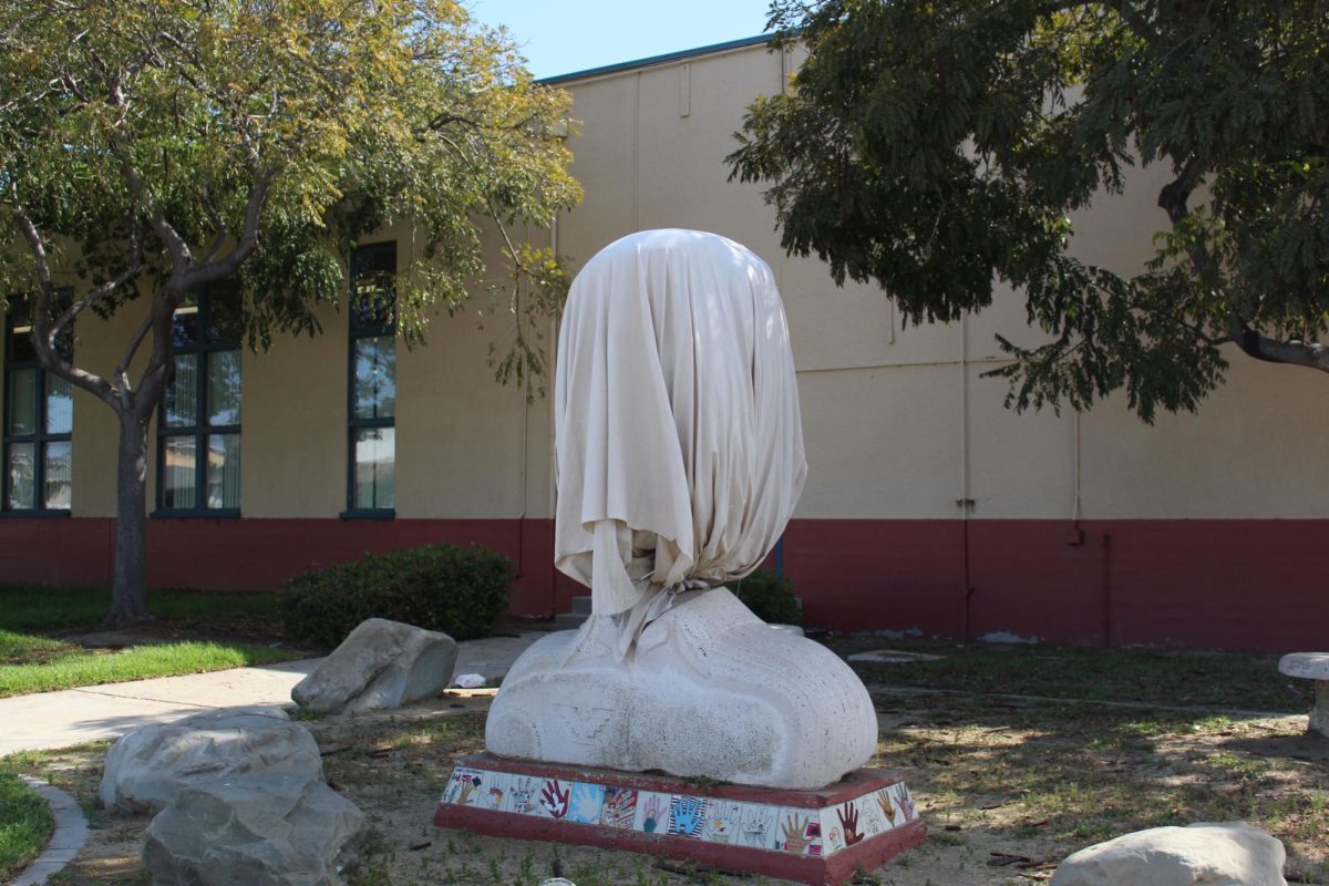 Una estatua frente a la escuela César Chávez tiene una sábana sobre ella en un intento de ocultar la identidad de la figura histórica que se ha vuelto problemático recientemente.

